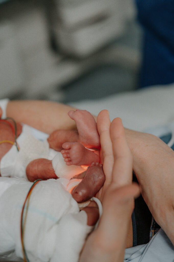 Neugeborenes im Krankenhausbett hält die Hand der Mutter