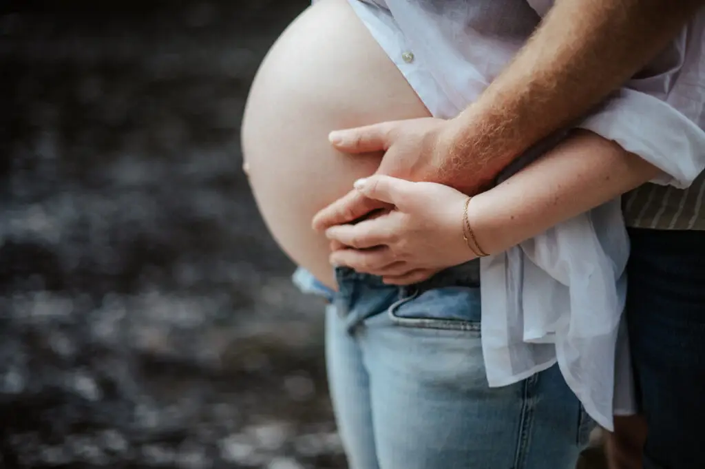 Schwangere Frau im Sommerkleid hält ihren Babybauch