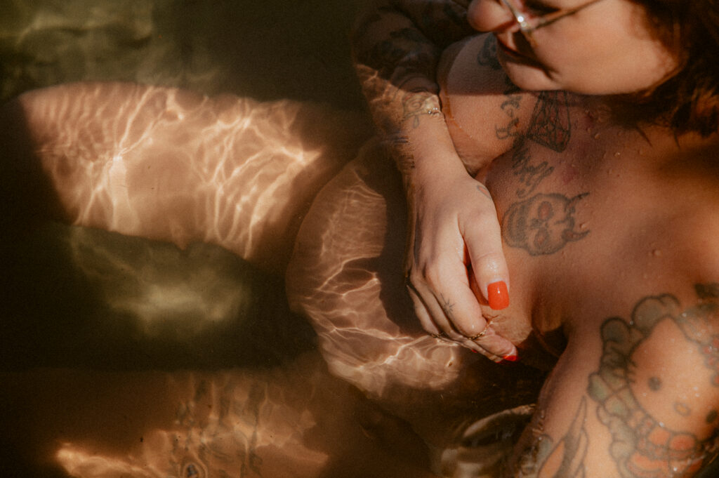 Schwangere mit Tattoos im Wasser, Lichtspiel auf der Haut
