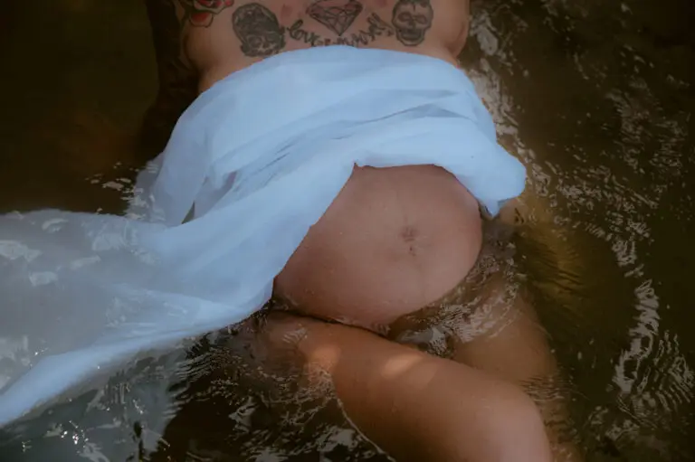 Babybauch mit weißem Tuch im Wasser