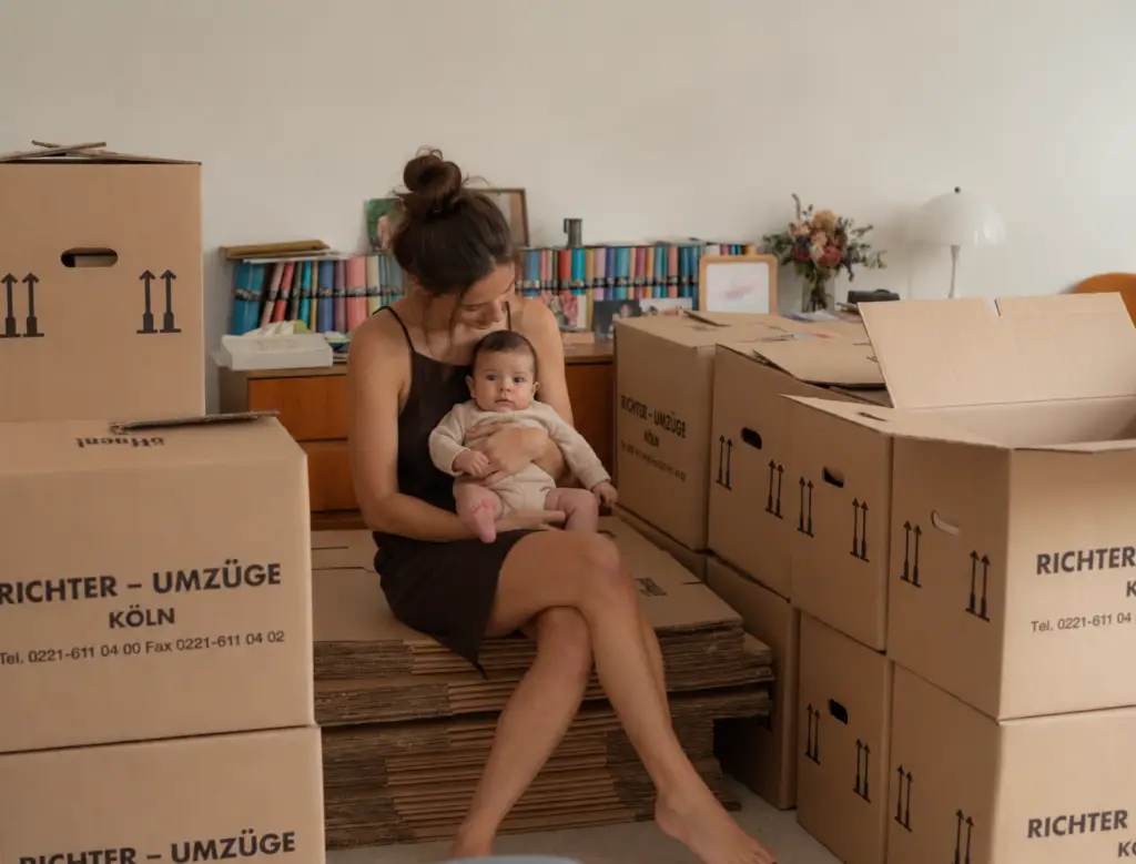 Mutter mit Baby zwischen Umzugskartons