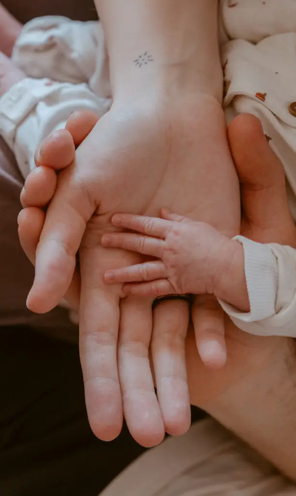 Babyhand liegt in den Händen von Mutter und Vater