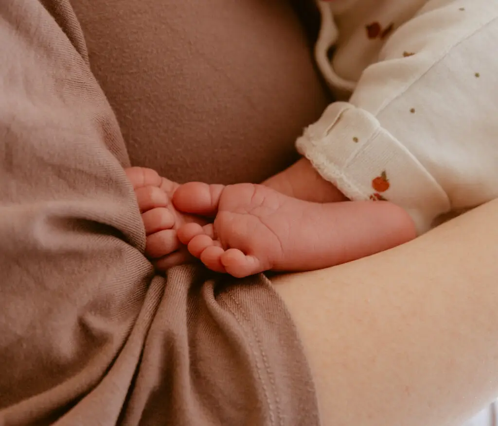 Babyfüße an der Brust der Mutter
