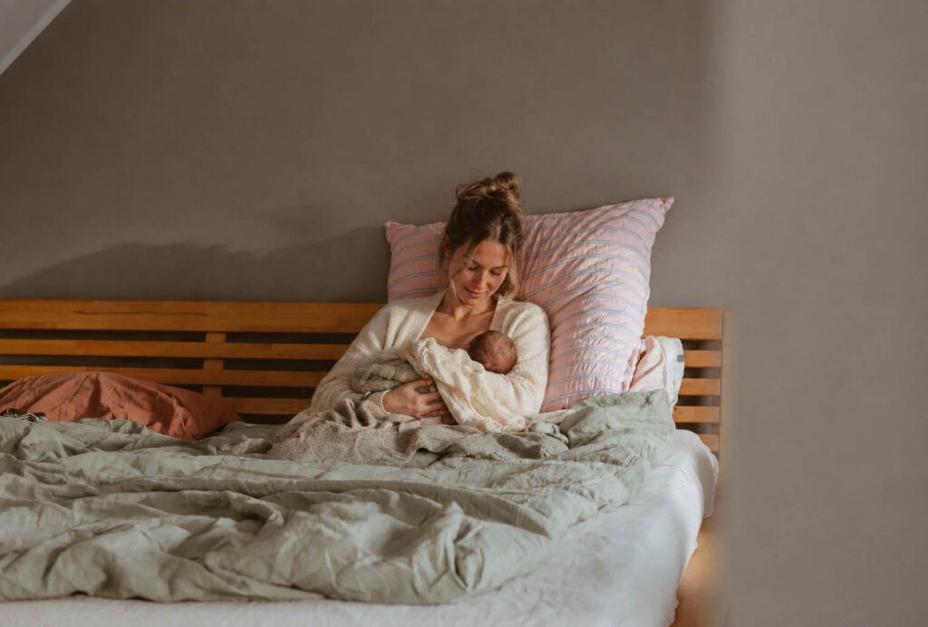 Mutter mit Neugeborenem im Bett im Wochenbett