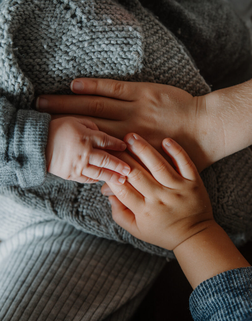 Babyhände zwischen den Händen der Eltern