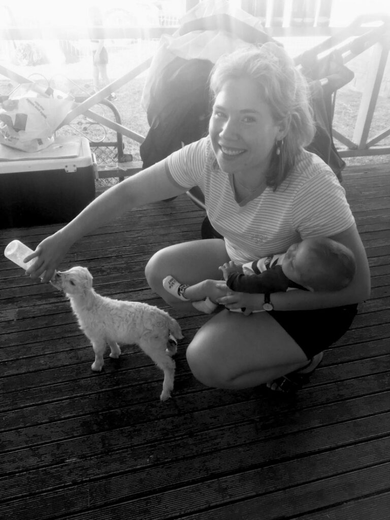 Céline hockt lachend mit Baby und Hund, Schwarz-Weiß