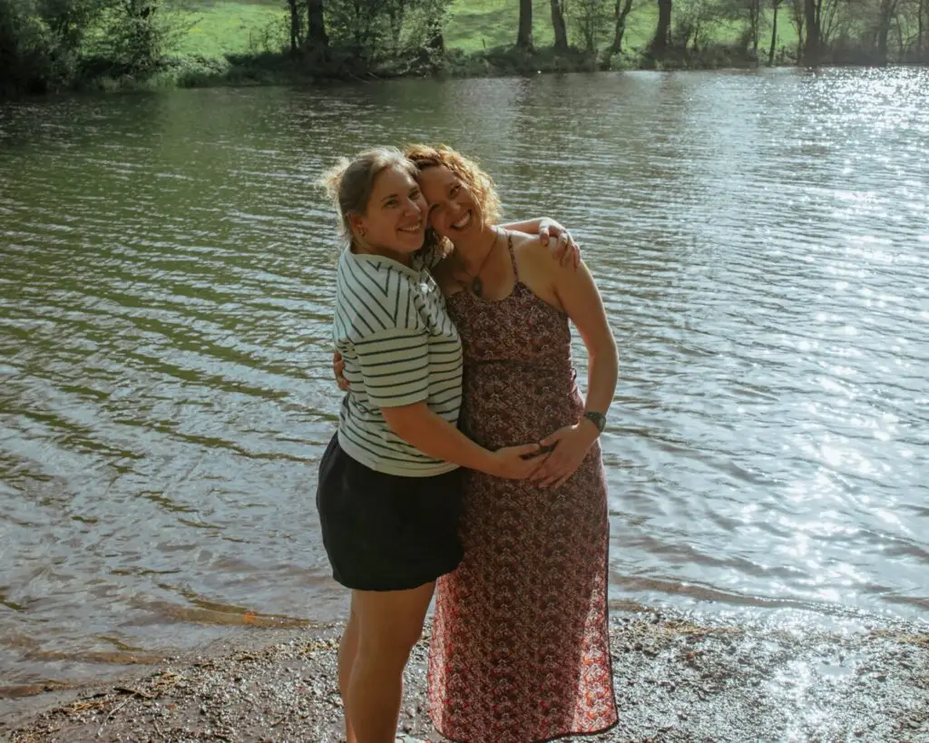 Céline umarmt eine schwangere Frau am See